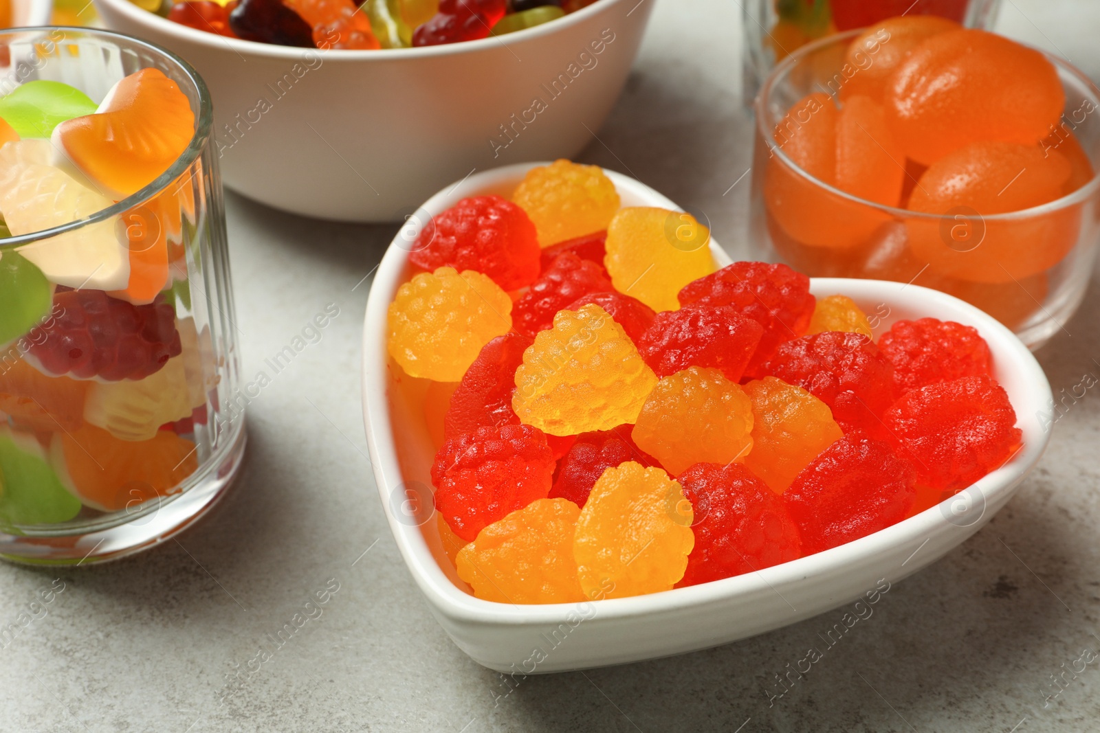 Photo of Delicious gummy candies on light grey table, closeup