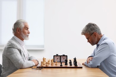 Photo of Men playing chess during tournament at table indoors