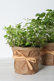 Different aromatic potted herbs on white wooden table, closeup