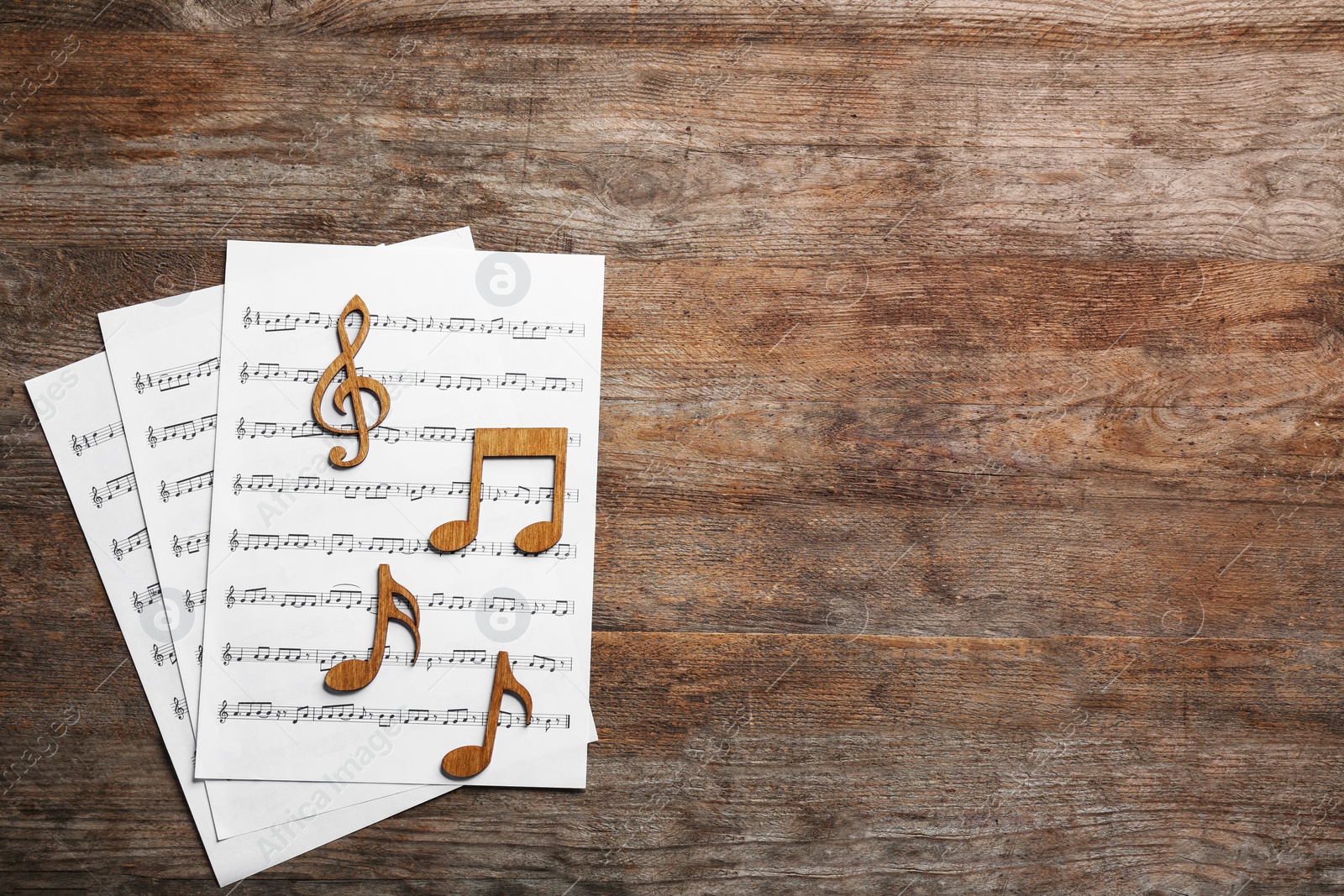 Photo of Music notes with sheets on wooden background, flat lay. Space for text