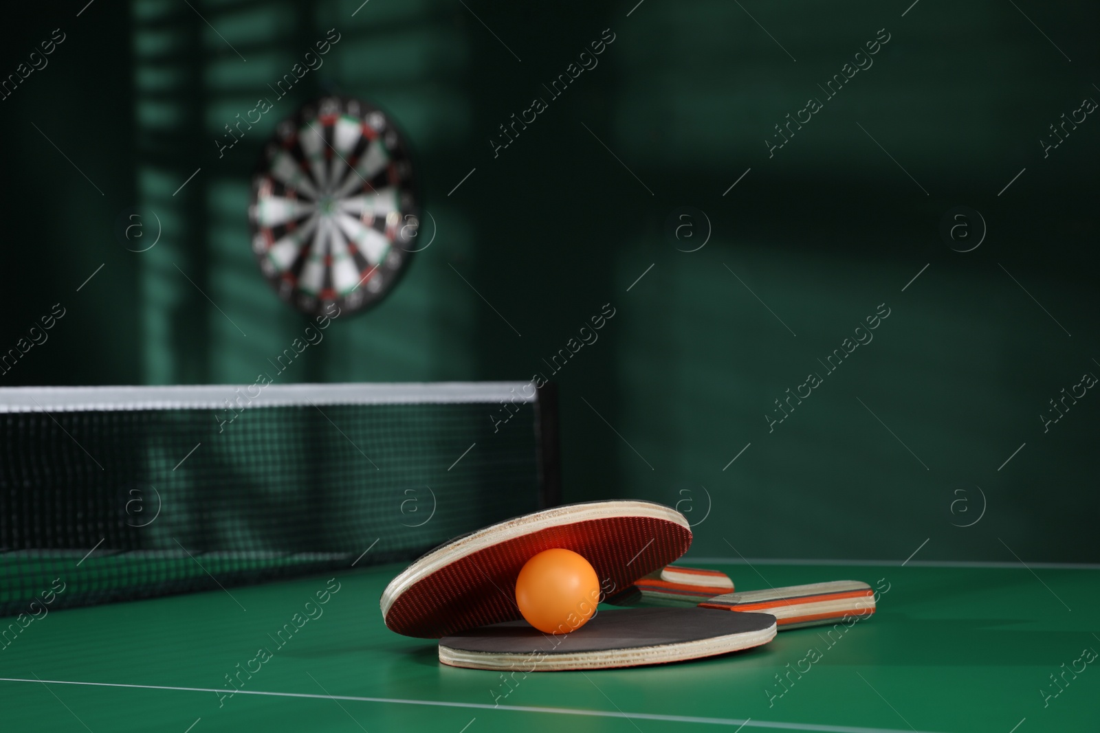 Photo of Rackets and ball on green ping pong table indoors. Space for text