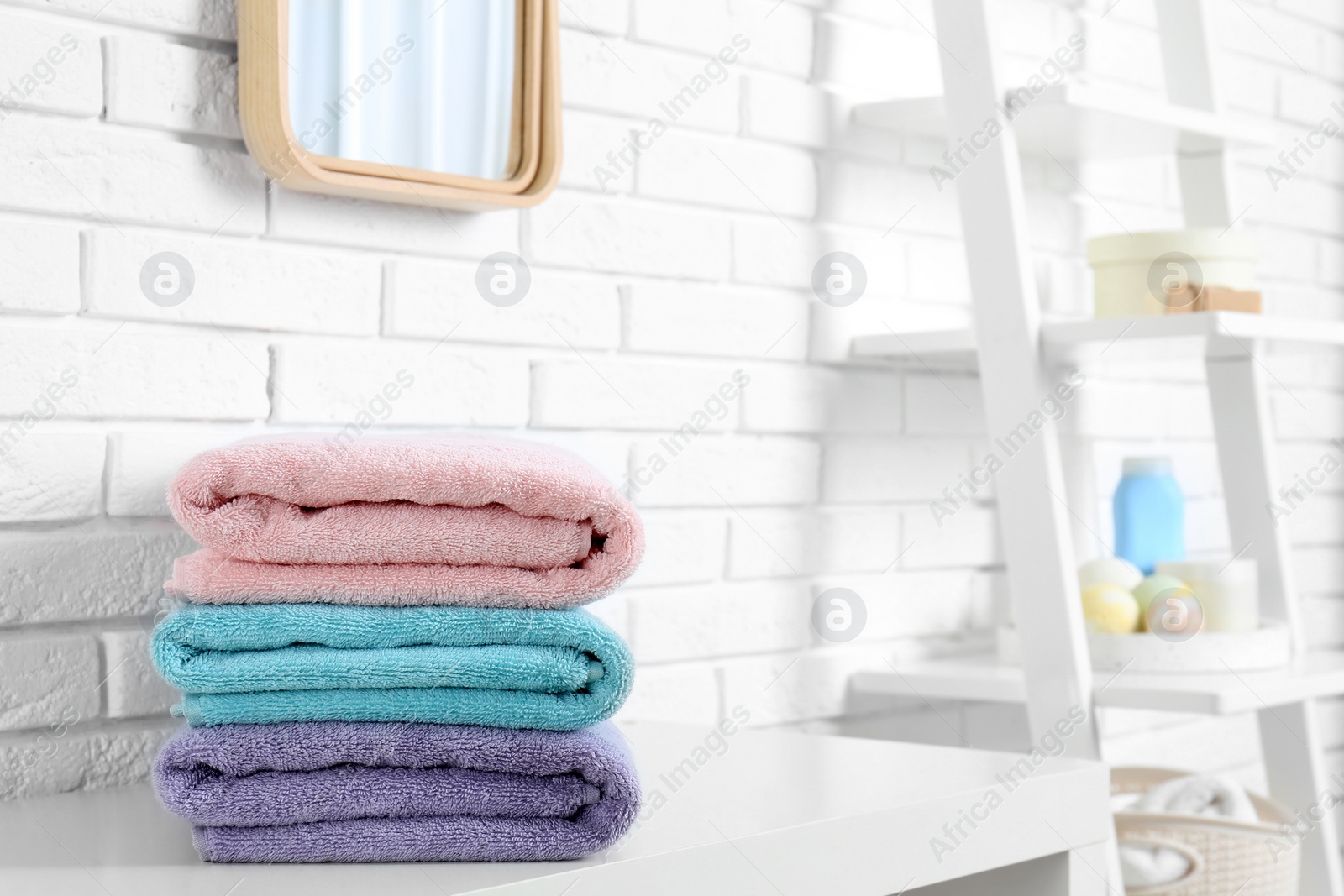 Photo of Stack of fresh towels on table in bathroom. Space for text