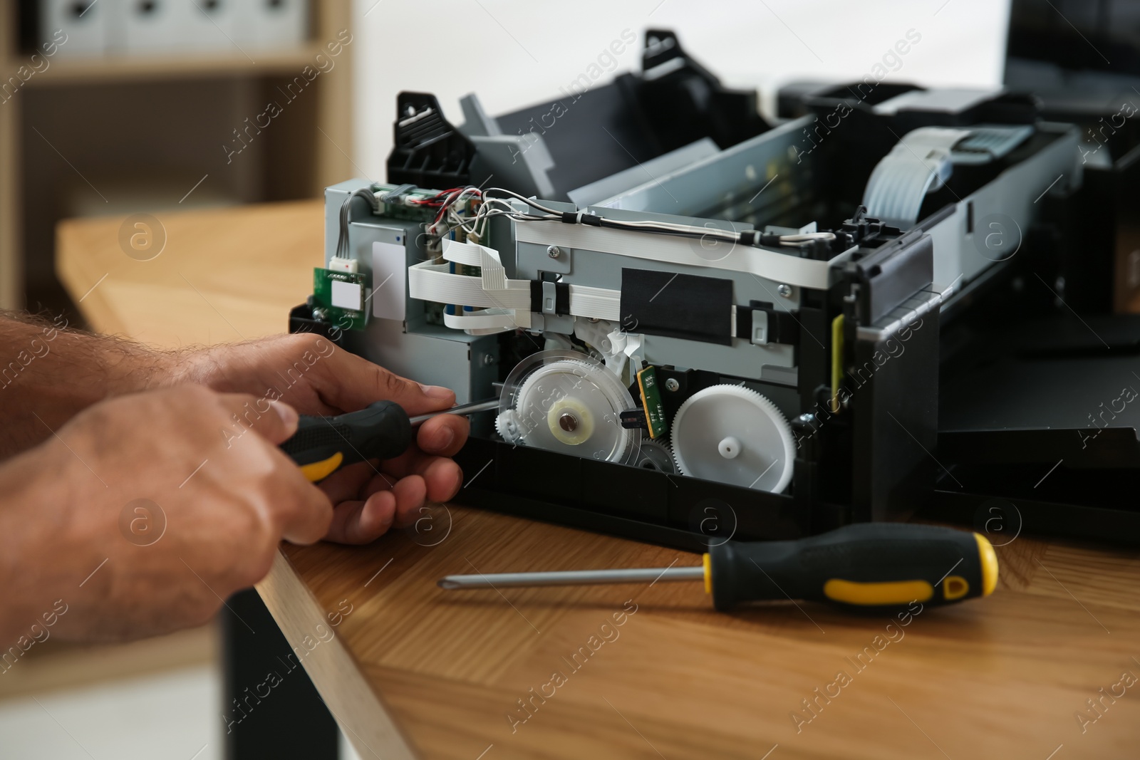 Photo of Repairman with screwdriver fixing modern printer indoors, closeup