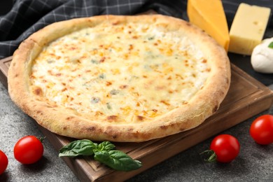 Photo of Delicious cheese pizza and ingredients on dark grey table