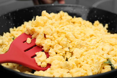 Photo of Stirring tasty scrambled eggs in wok pan, closeup