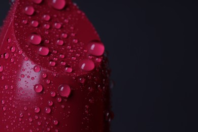 Photo of Red lipstick with water drops on dark gray background, macro view. Space for text