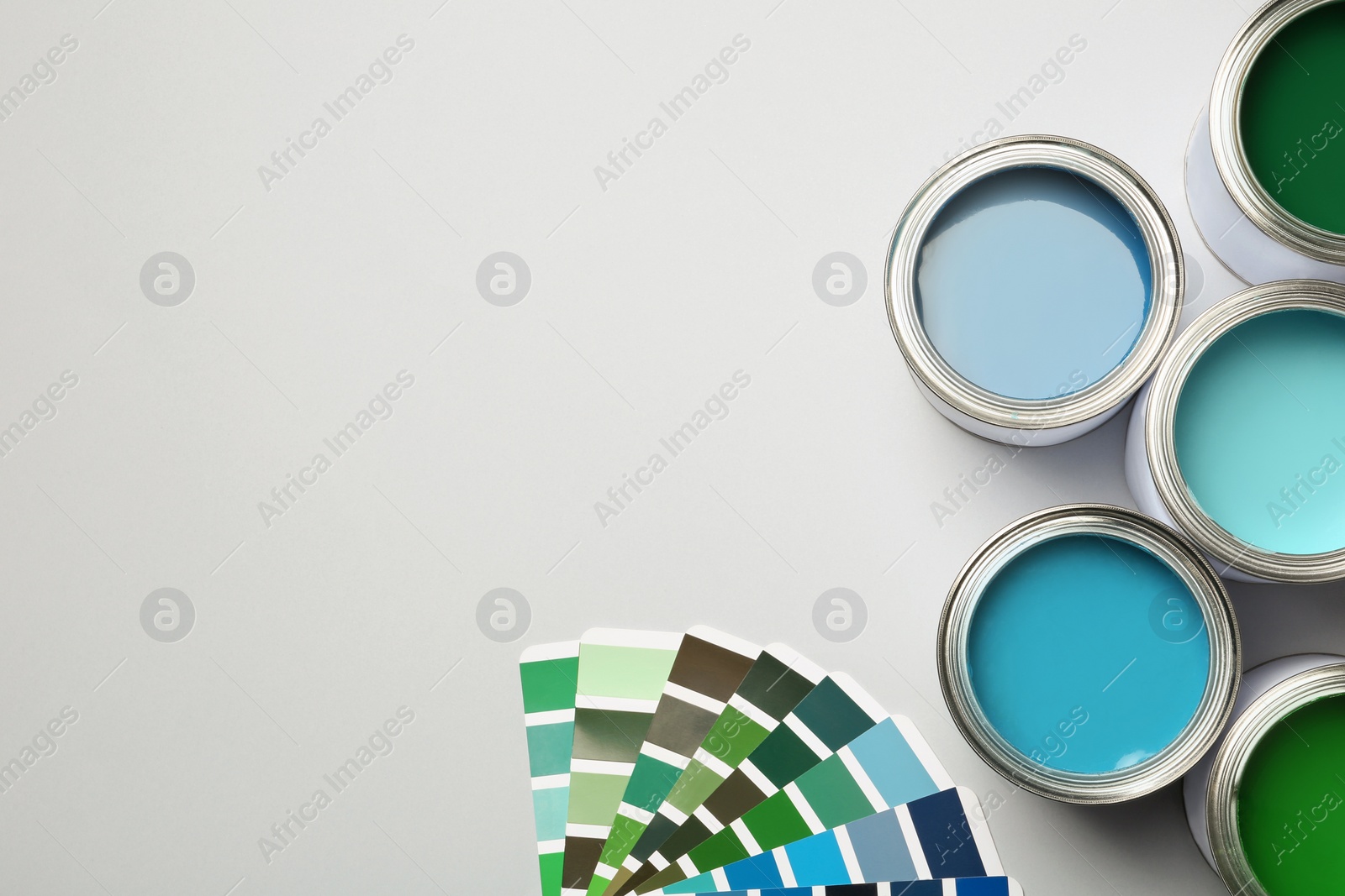 Photo of Paint cans and color palette on white background, top view. Space for text