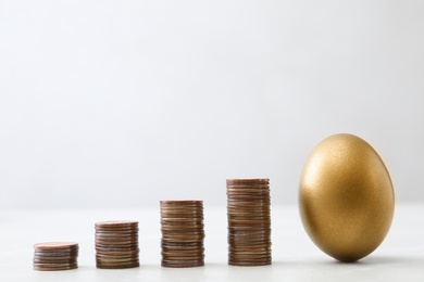 Photo of Gold egg and stacks of coins on table