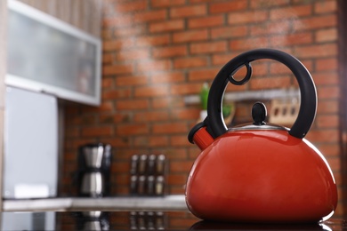 Modern kettle with whistle on stove in kitchen, space for text