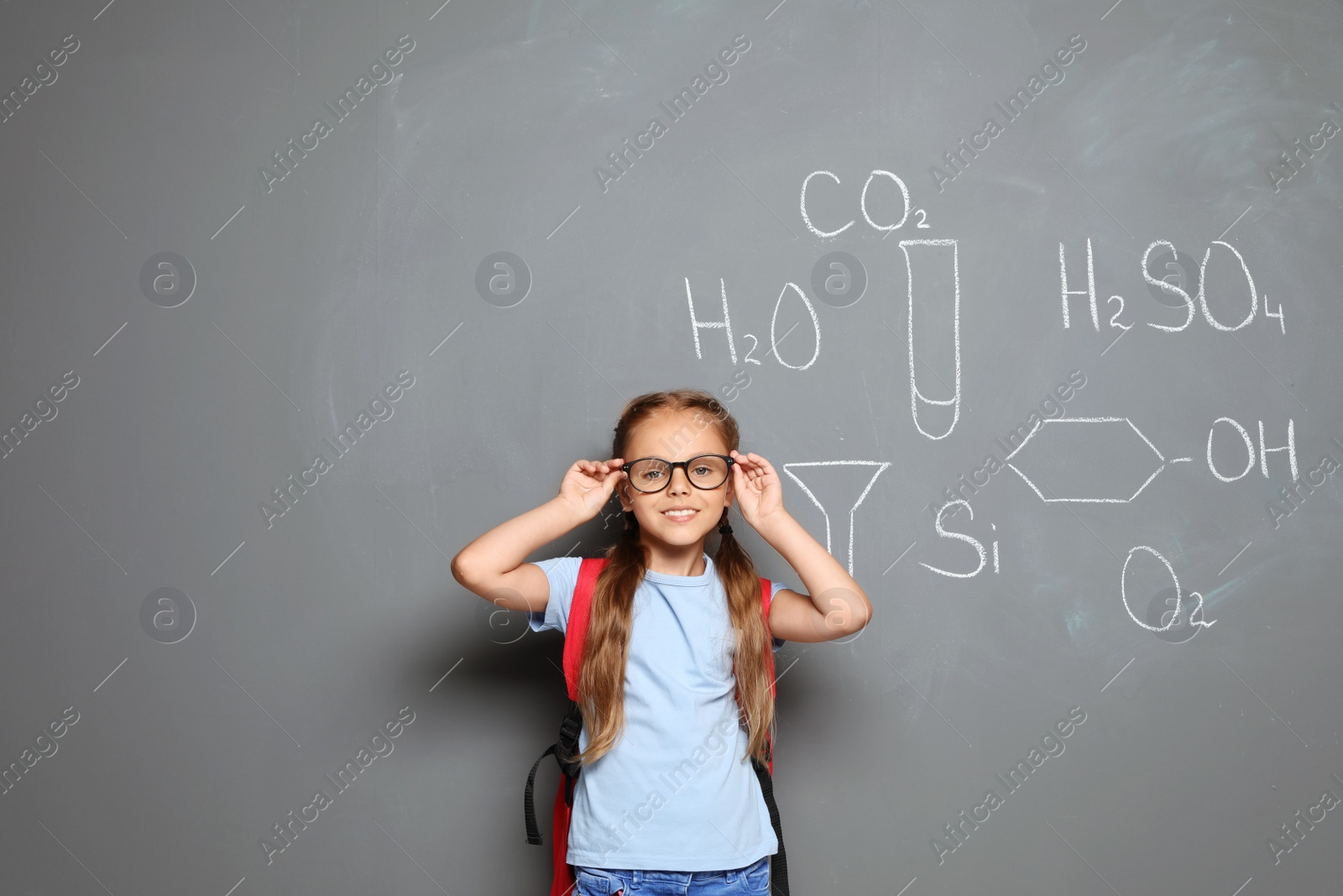 Photo of Little school child with backpack and chemical formulas on grey background