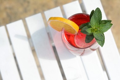 Photo of Glass of delicious cocktail on white wooden table, top view with space for text. Refreshing drink
