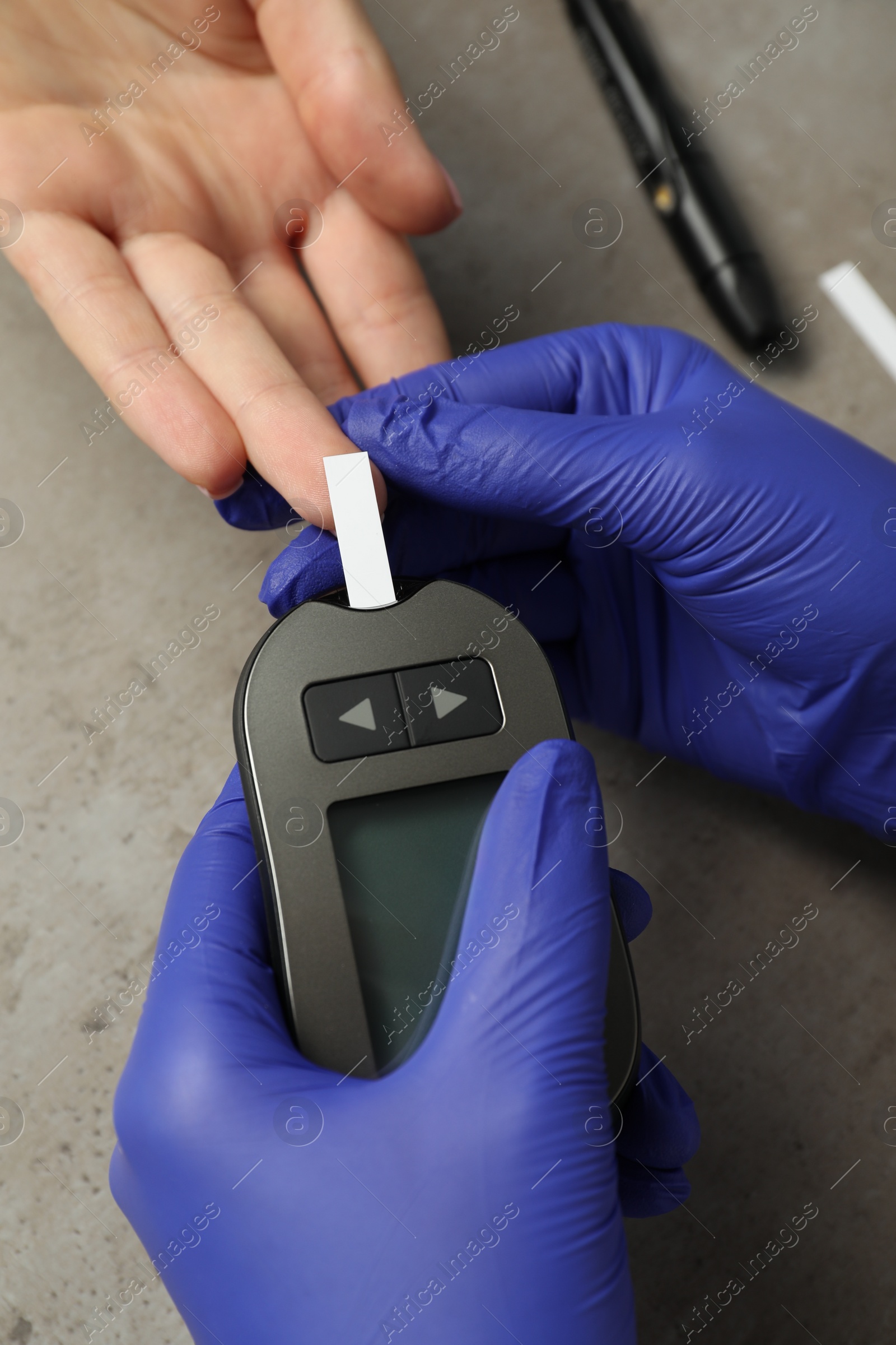 Photo of Diabetes. Doctor checking patient's blood sugar level with glucometer at gray table, top view