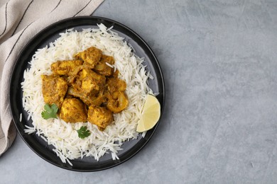 Photo of Delicious chicken curry with rice on grey table, top view. Space for text