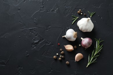 Photo of Fresh raw garlic and spices on black table, flat lay. Space for text