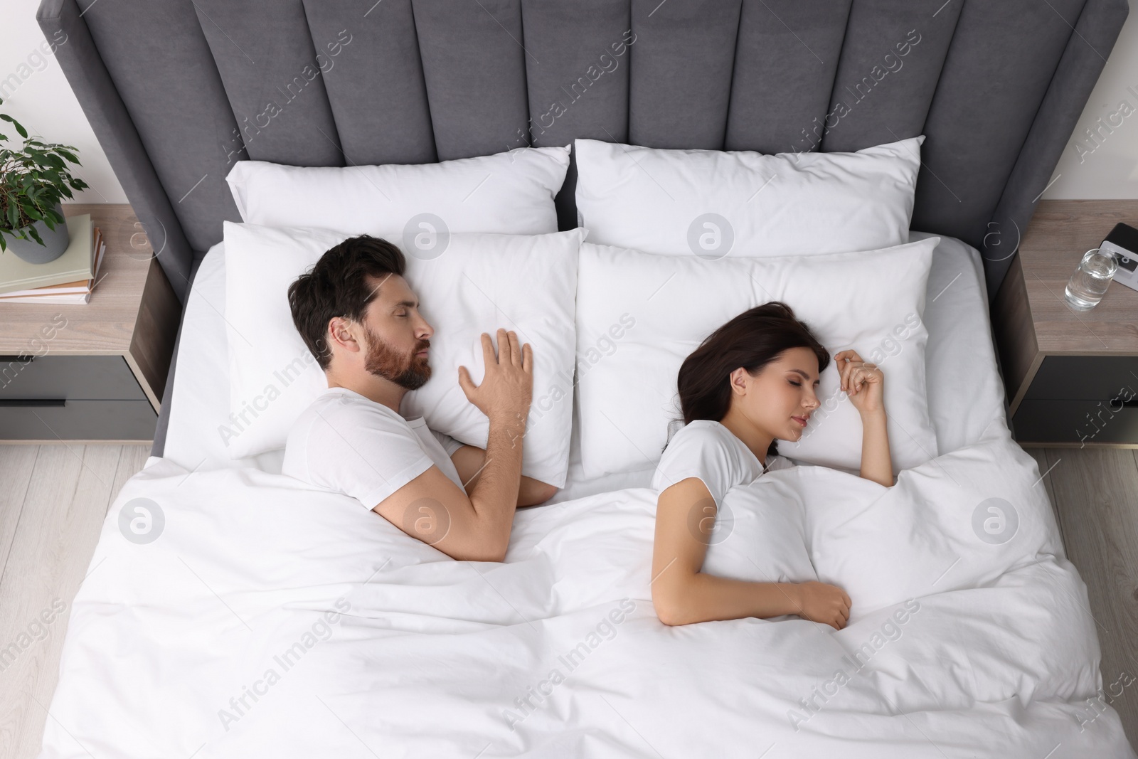 Photo of Lovely couple sleeping together in bed at home, top view