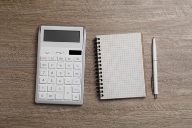 Photo of Calculator and office stationery on wooden table, flat lay. Space for text