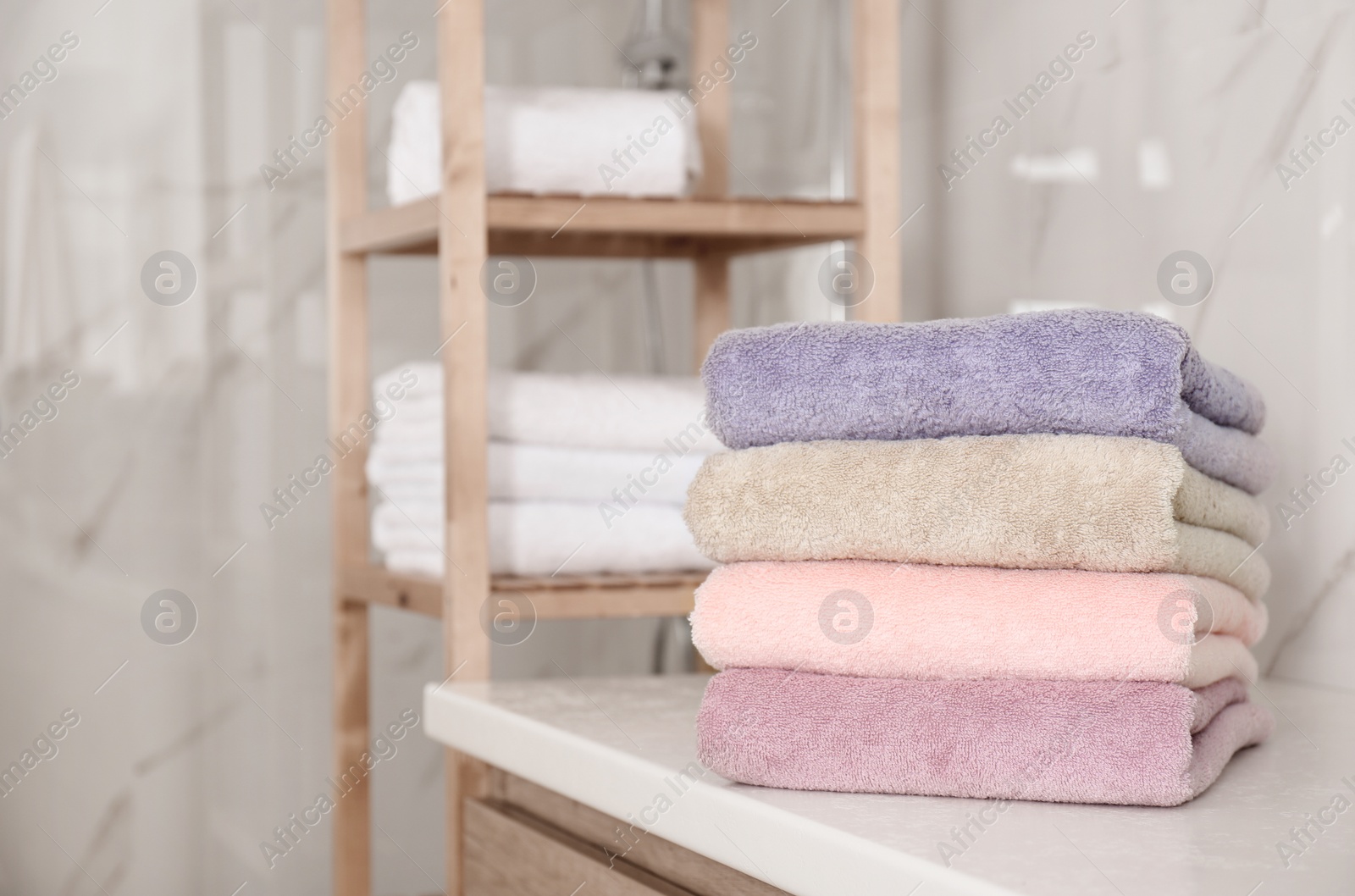 Photo of Stack of color towels on white table in bathroom. Space for text