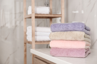 Photo of Stack of color towels on white table in bathroom. Space for text