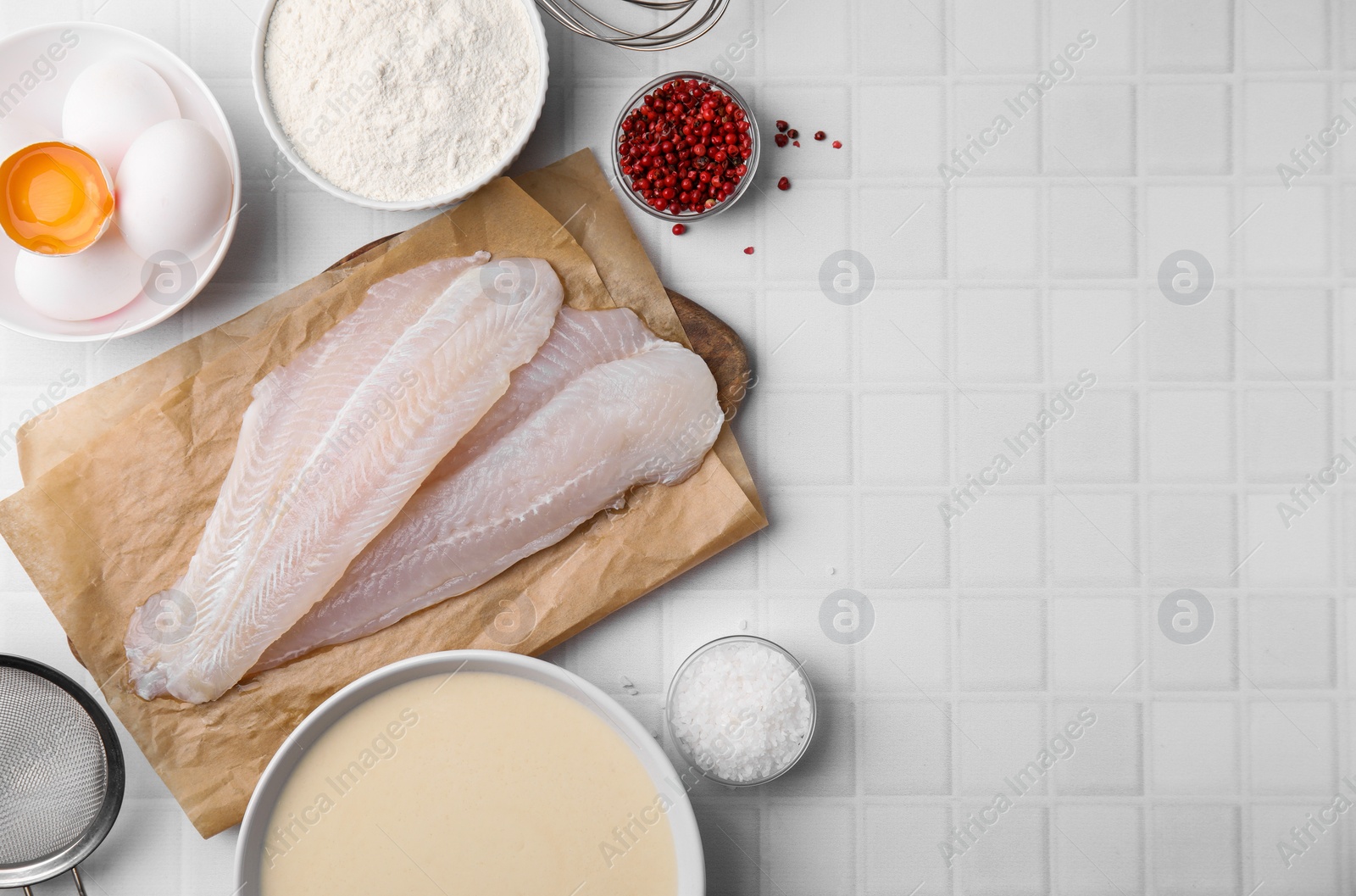 Photo of Different ingredients for batter and raw fish fillet on white tiled table, flat lay. Space for text