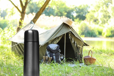 Image of Modern thermos outdoors, space for text. Camping season 