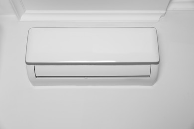 Modern air conditioner on white wall indoors