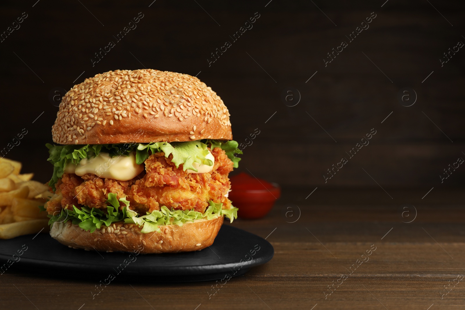 Photo of Delicious burger with crispy chicken patty on wooden table. Space for text