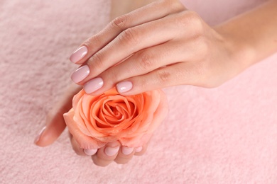 Photo of Closeup view of beautiful female hands with rose on towel. Spa treatment