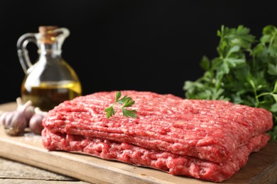 Photo of Raw ground meat, garlic, oil and parsley on wooden table, closeup