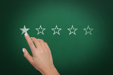 Image of Quality rating. Woman pointing at stars on chalkboard, closeup