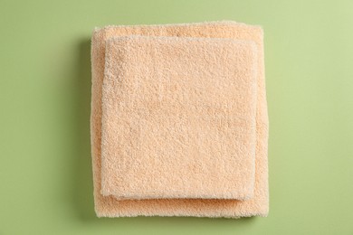 Photo of Soft folded towels on green background, top view