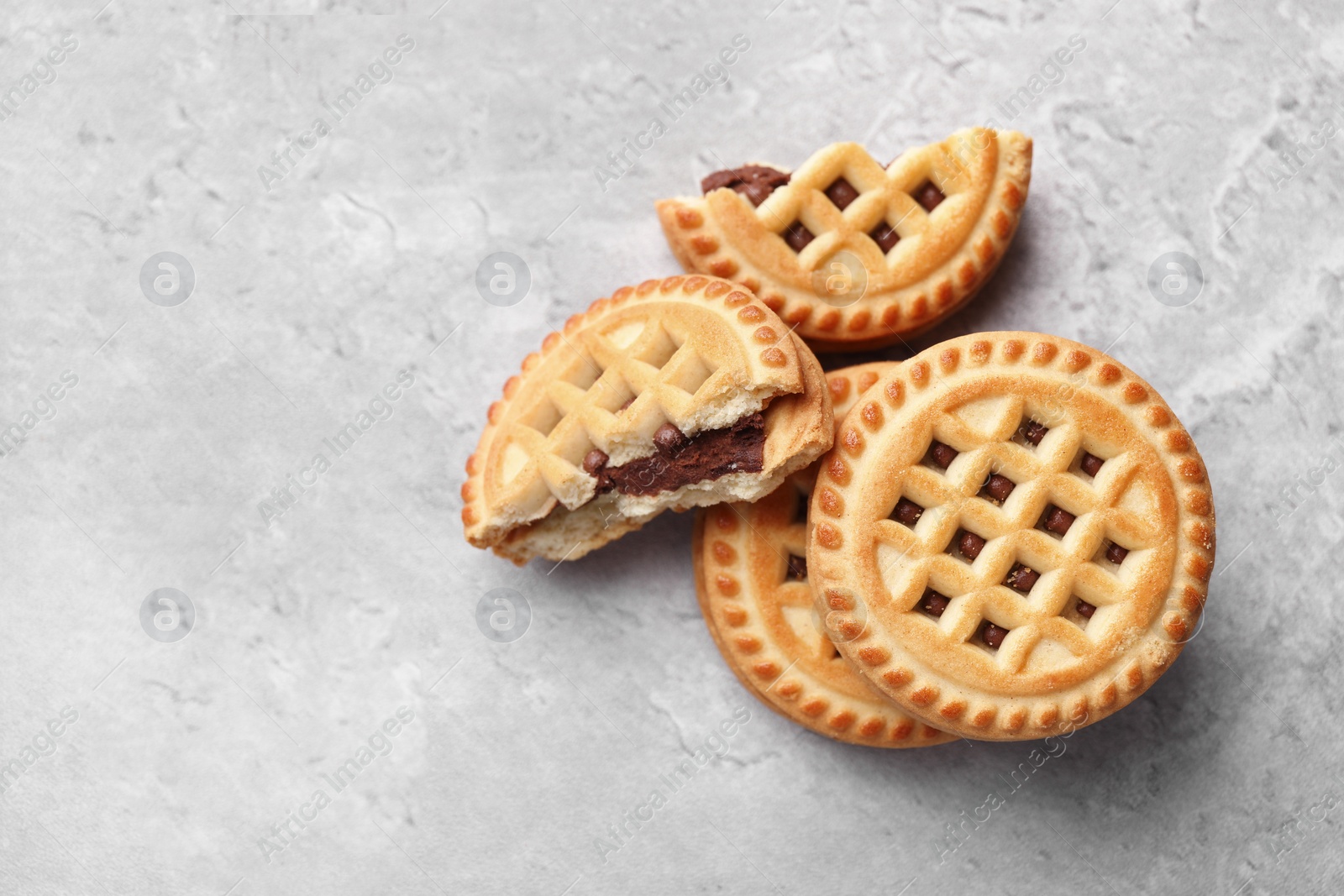 Photo of Tasty sandwich cookies with cream on grey table, flat lay. Space for text