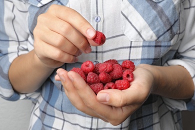 Photo of Woman holding heap of delicious ripe raspberries, closeup