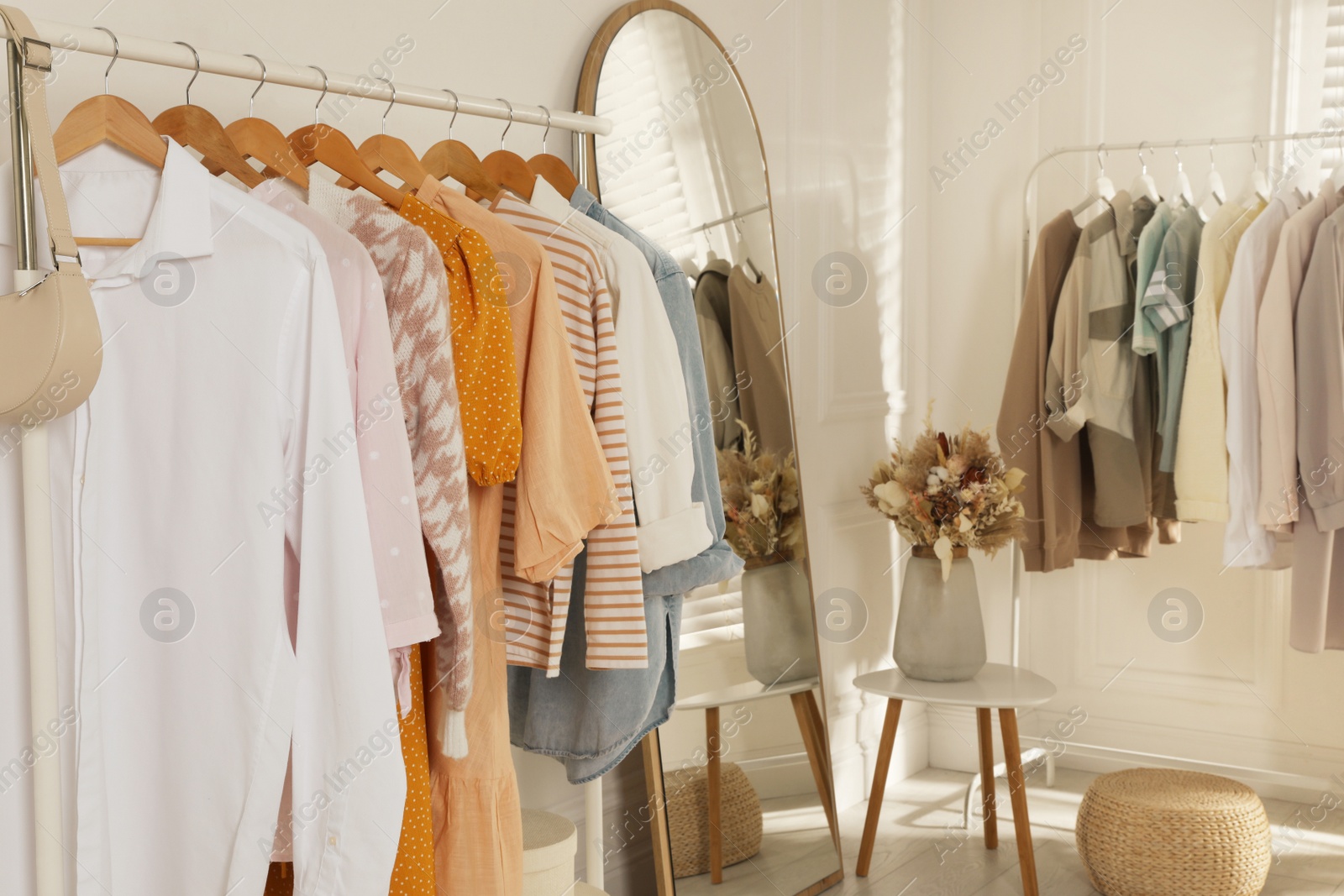 Photo of Modern dressing room interior with stylish clothes and beautiful dry flowers