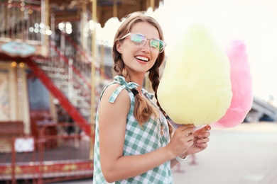 Young woman with cotton candies in amusement park