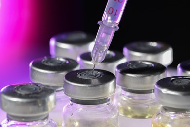 Photo of Filling syringe with medicine from vial on color background, closeup
