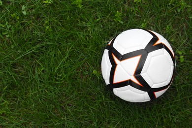 Photo of New soccer ball on fresh green grass outdoors, top view. Space for text