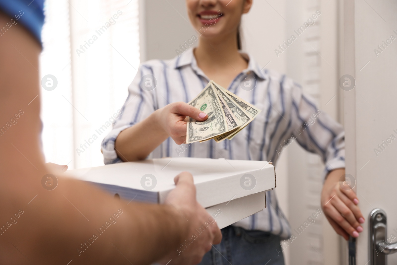 Photo of Woman giving tips to deliveryman indoors, closeup