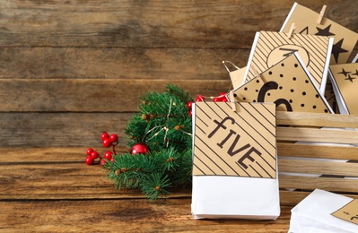 Photo of Paper bags and festive decor on wooden table, space for text. Christmas advent calendar