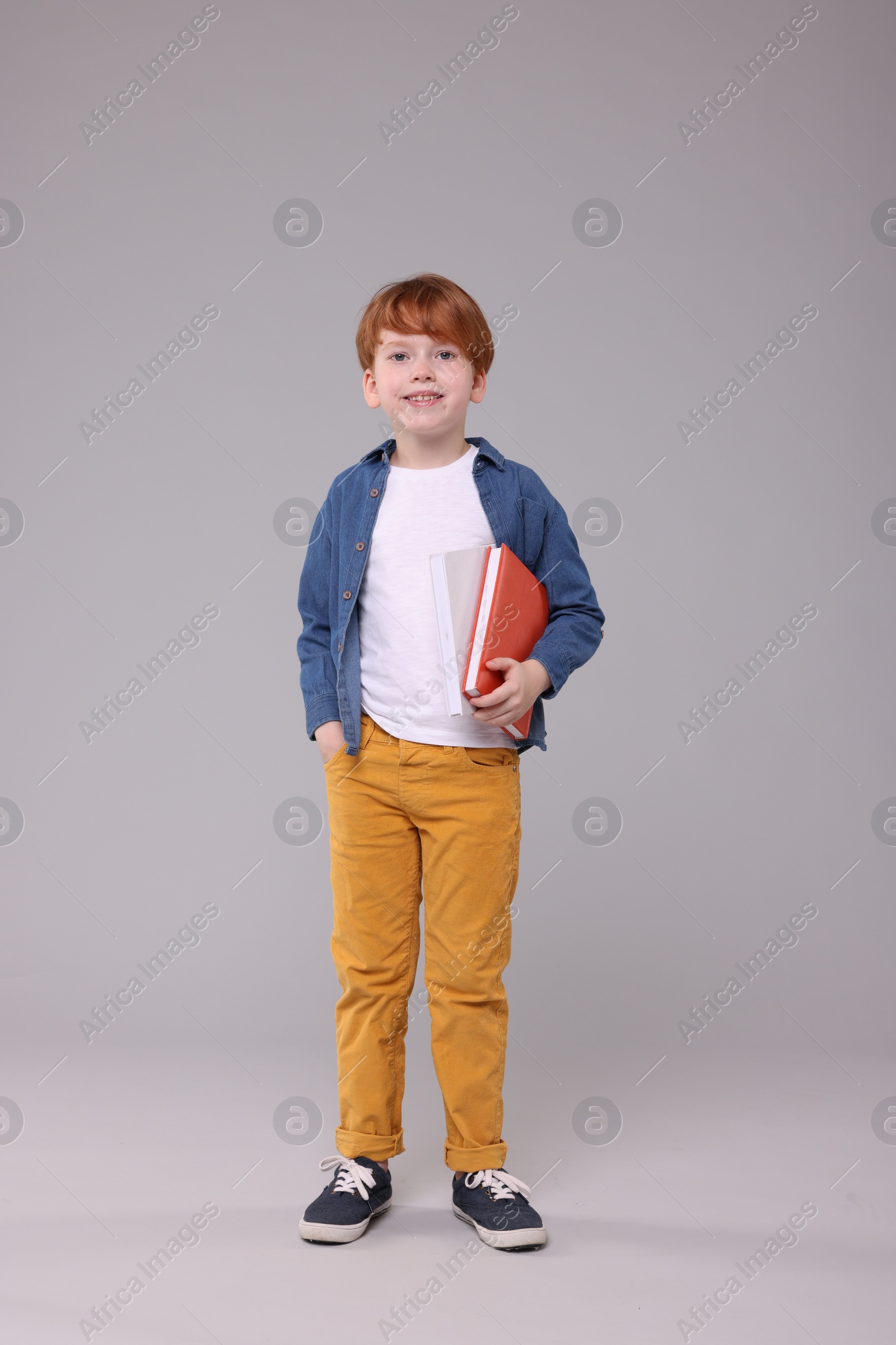 Photo of Happy schoolboy with books on grey background