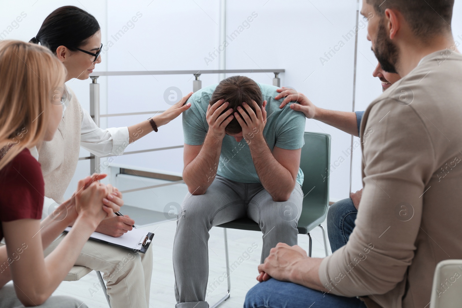 Photo of Psychotherapist working with group of drug addicted people at therapy session indoors