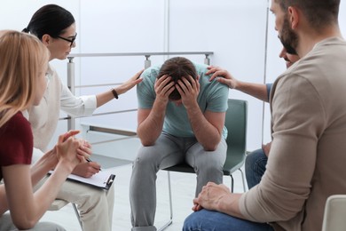 Psychotherapist working with group of drug addicted people at therapy session indoors