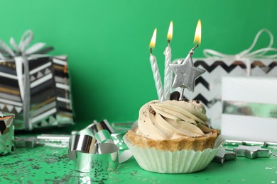 Birthday cupcake with candles on green background