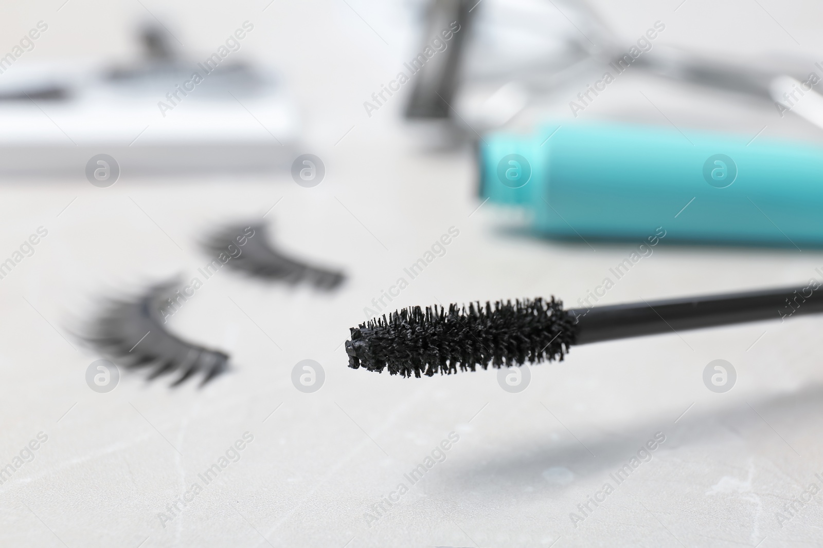 Photo of Mascara brush and false eyelashes on table, closeup