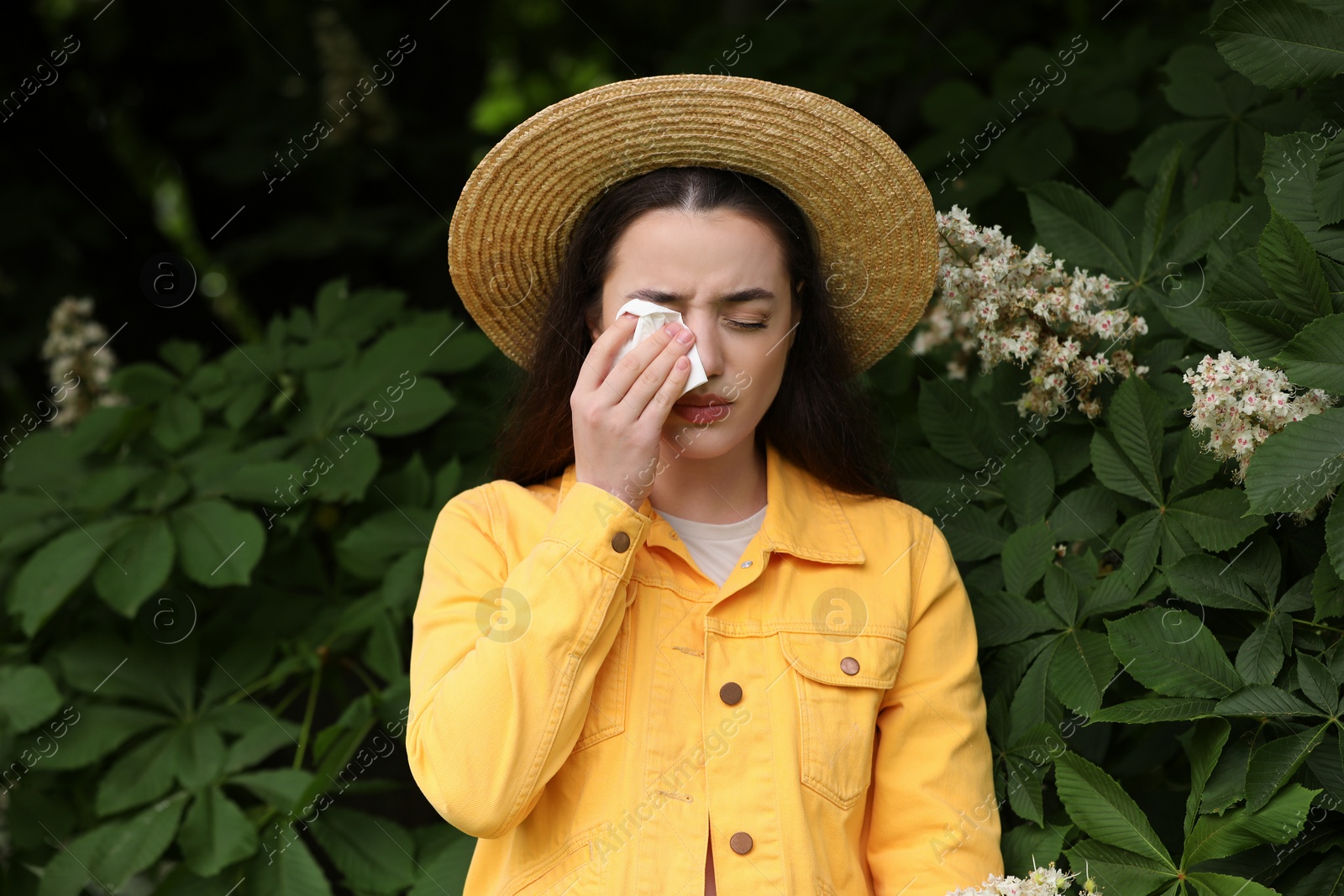 Photo of Woman suffering from seasonal spring allergy near tree in park