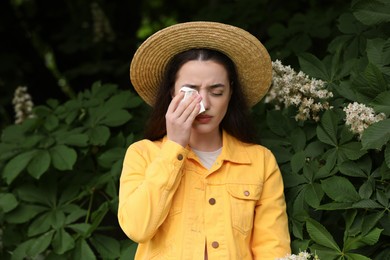 Woman suffering from seasonal spring allergy near tree in park