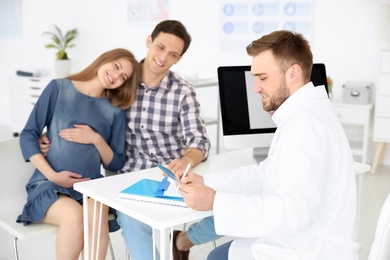 Photo of Gynecology consultation. Doctor showing ultrasound of baby to future parents in clinic