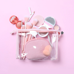 Photo of Plastic cosmetic bag with makeup products and beauty accessories on pink background, flat lay