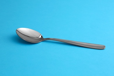 Photo of Clean empty table spoon on blue background