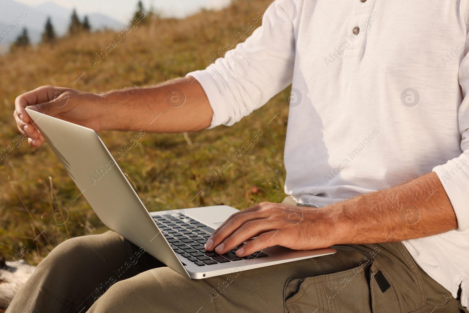 Photo of Man working with laptop outdoors on sunny day, closeup