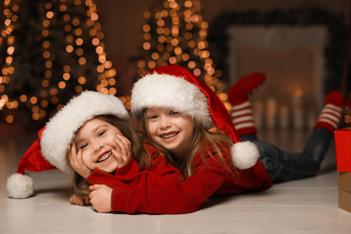 Photo of Cute little children wearing Santa hats at home. Christmas time